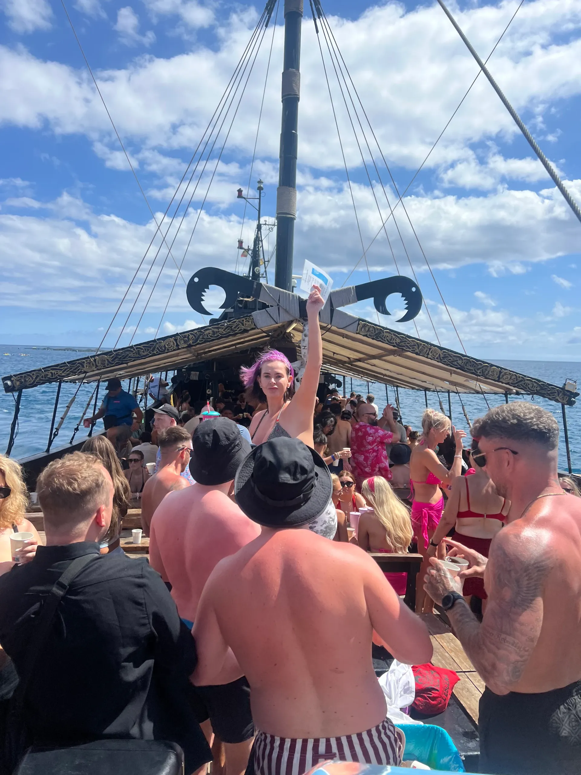 Crowded tenerife boat party with guests dancing and celebrating on deck under blue sky