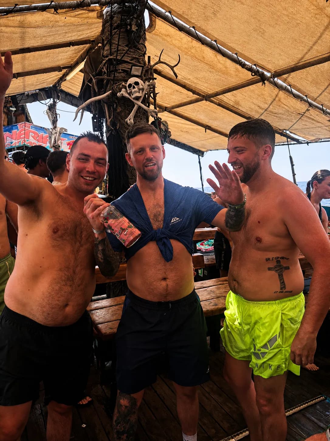 Three men holding drinks on a pirate-themed Tenerife boat party