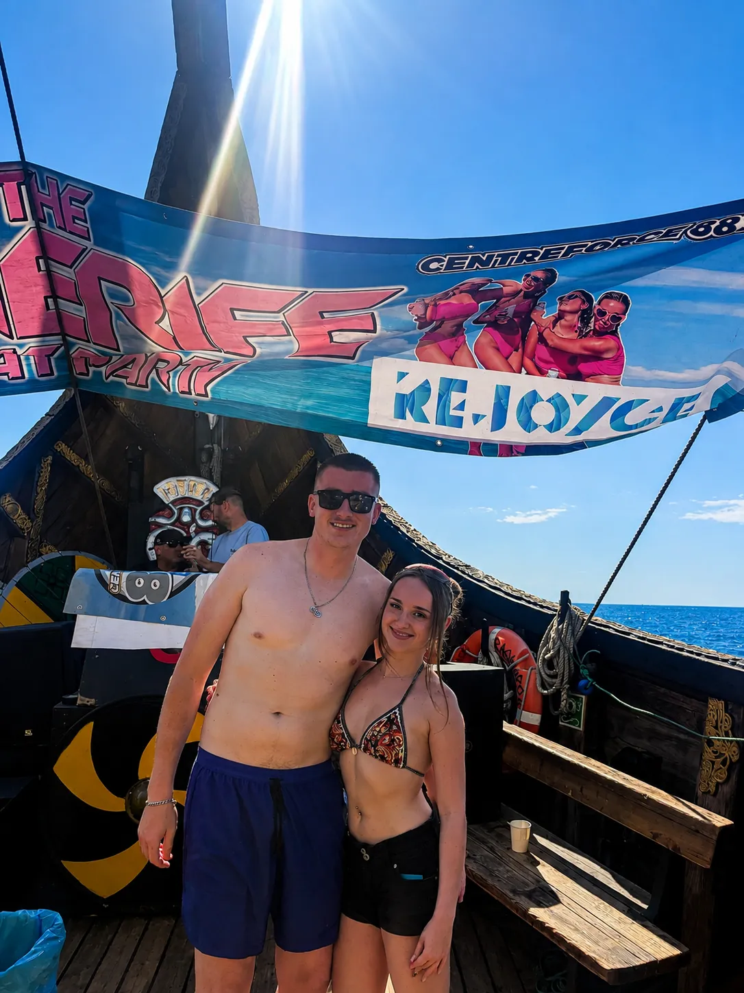 Couple posing on traditional boat deck with sea in background