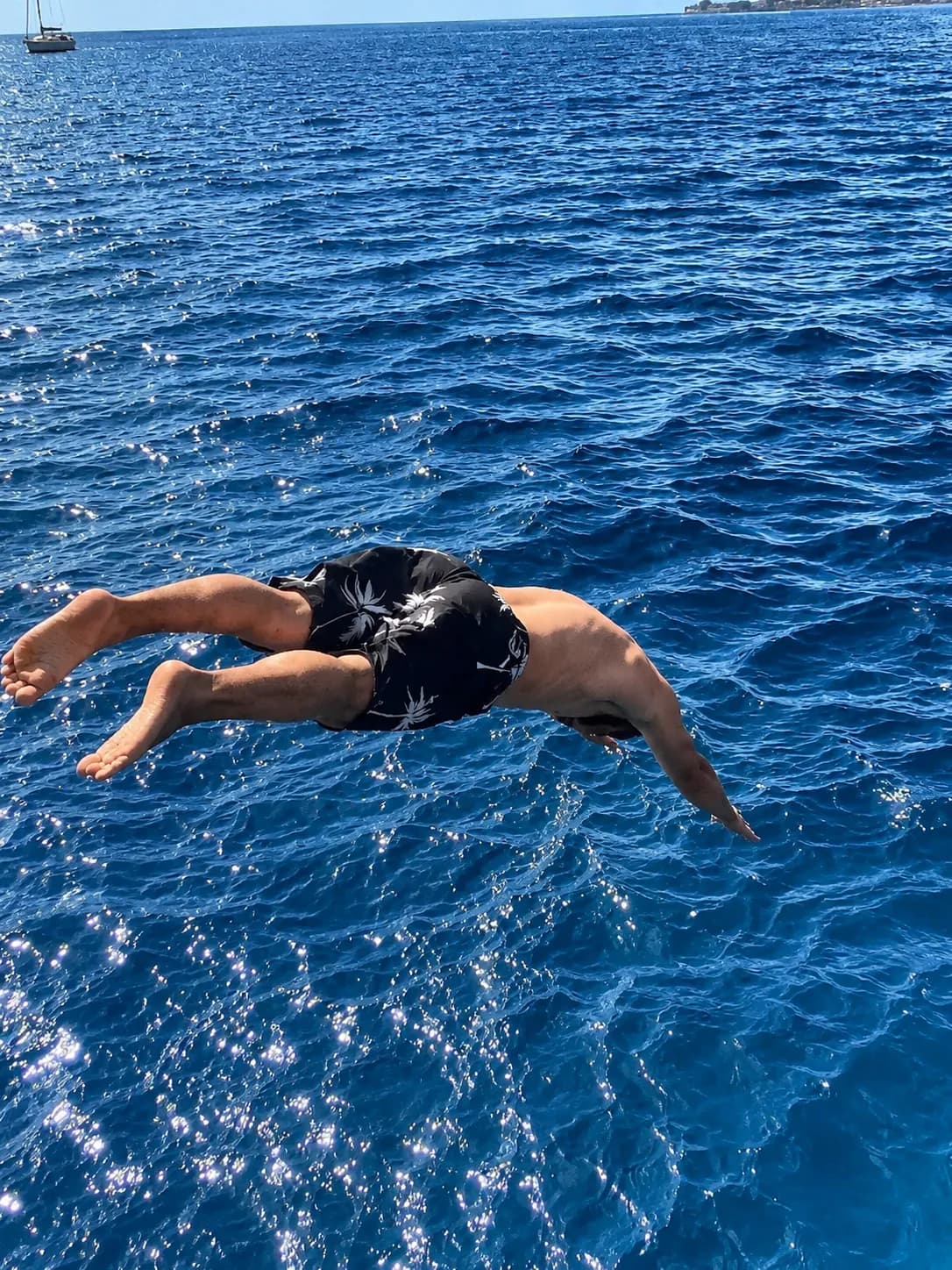 Person swimming freestyle in clear blue ocean water during boat party
