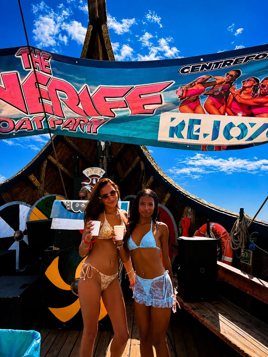 Two women in bikinis posing on pirate-themed boat party deck